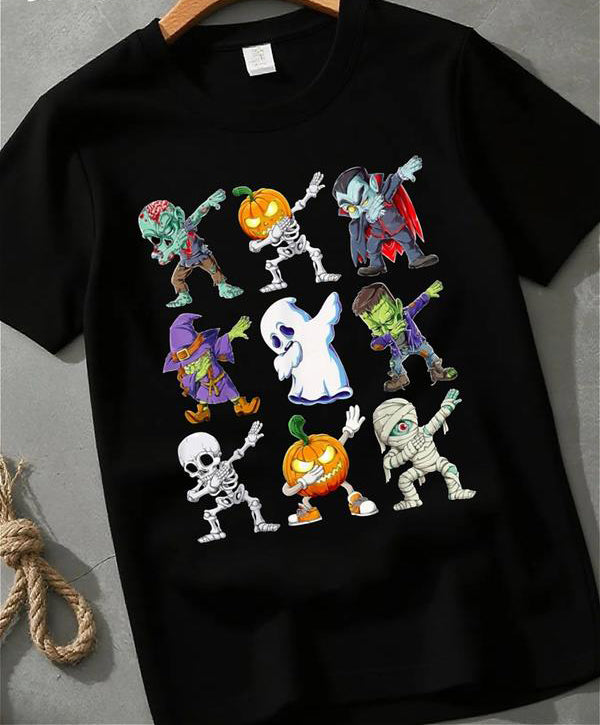 Black graphic T-shirt with cartoon Halloween characters dabbing, including ghost, zombie, pumpkin, witch, skeleton, and mummy