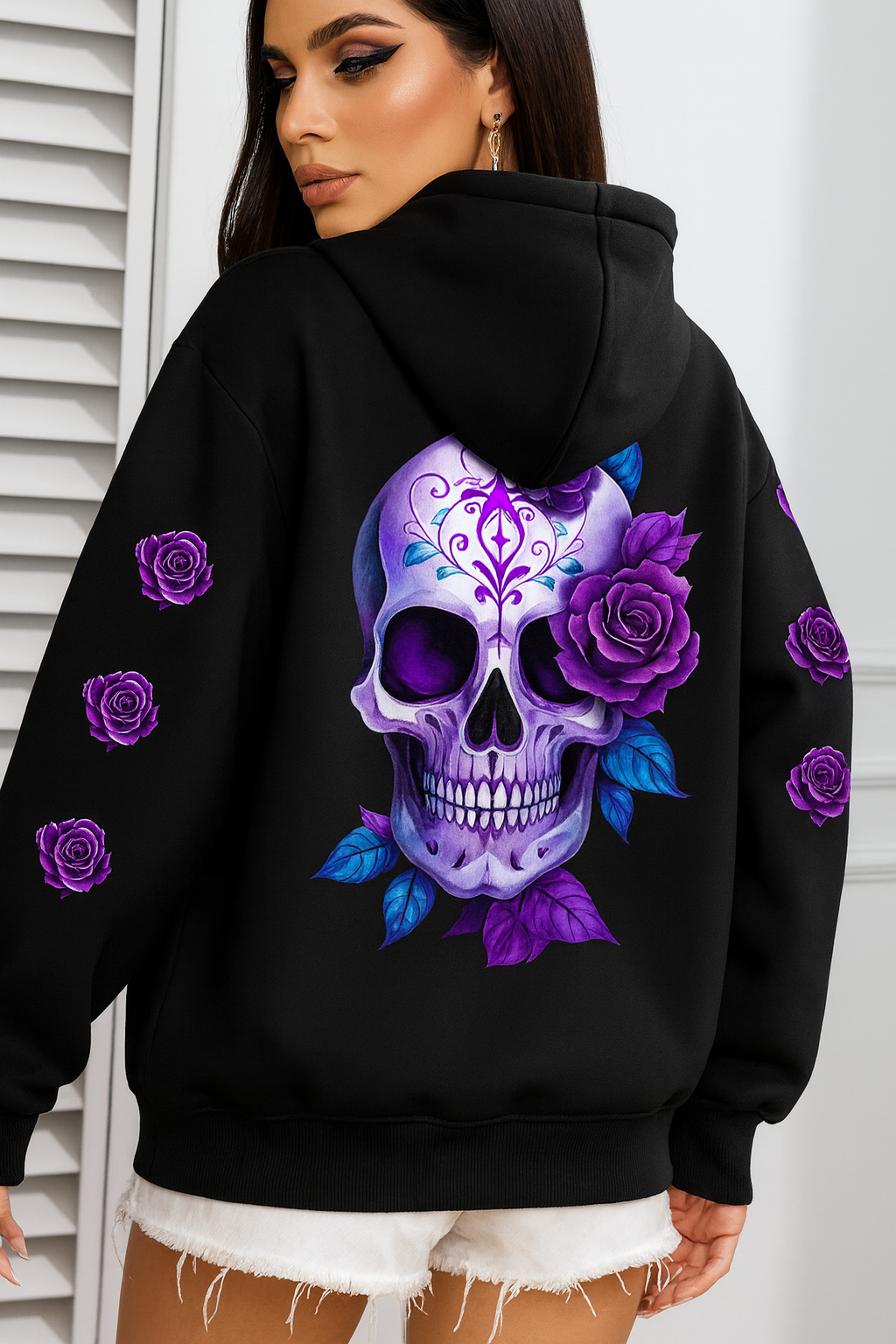 Model wearing black hoodie with purple Sugar Skull and rose design, standing in front of white shutters
